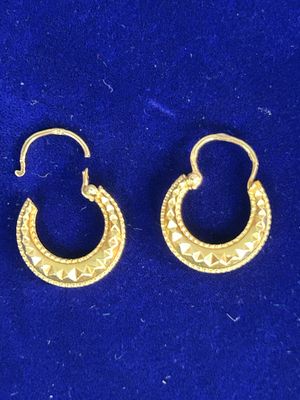 une paire de boucles d'oreilles créoles en or sur fond bleu