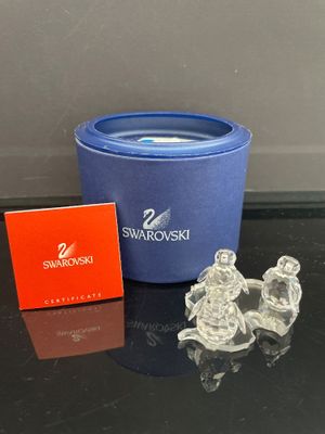 des figurines en cristal Swarovski dans une boîte bleue et une boîte rouge, posées sur une table noire