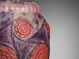 a purple vase with red flowers on it sitting on a table