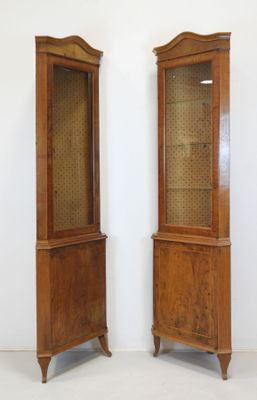 pair of antique wooden display cabinets with glass doors in a white room