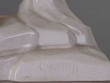 a white statue of a man sitting on top of a table
