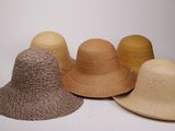 plusieurs chapeaux sont alignés sur une surface blanche