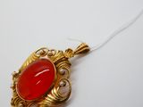 une image représentant un collier orné d'une pierre rouge sur fond blanc