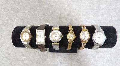several different watches are displayed on a black display stand
