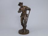 bronze statue of a man with a cane and hat on a white background