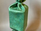 sculpture représentant un vase vert posé sur un socle noir, sur fond blanc