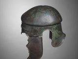 a bronze helmet with a face on the side of it
