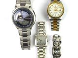 two watches and a watch bracelet are sitting on a white surface