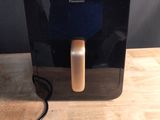 un distributeur d'eau noir et doré posé sur une table en bois