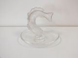a glass seahorse on a glass plate on a white surface