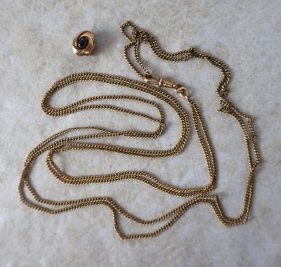 gros plan d'un collier en or avec une chaîne sur une surface blanche