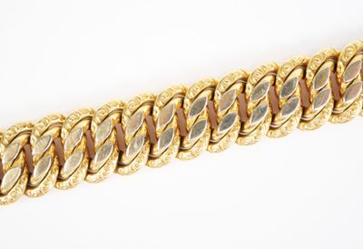 gros plan d'un bracelet en chaîne en or sur une surface blanche