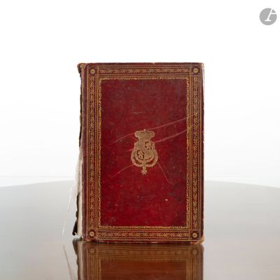 un livre rouge posé sur une table, orné d'un emblème doré