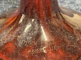 a red vase with a brown base on a blue carpet