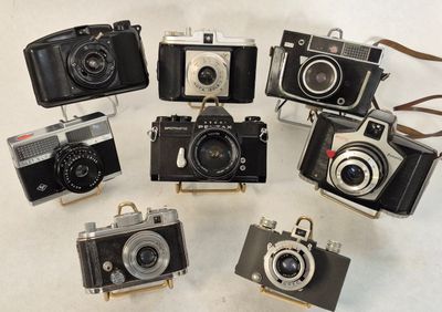 several old cameras are arranged in a circle on a white surface