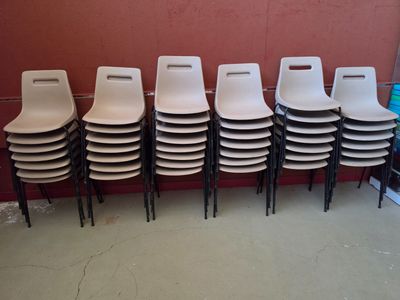des rangées de chaises en plastique blanc devant un mur rouge