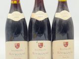 trois bouteilles de vin rouge sont alignées sur une surface blanche