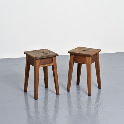 deux petits tabourets en bois posés sur un sol en béton