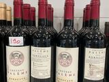 bottles of red wine are lined up on a shelf in a store