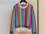multicolored sweater hanging on a hanger in front of a white wall