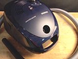 un aspirateur posé sur une table, muni d'un tuyau