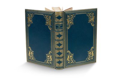 un livre ouvert, à la couverture bleue, posé sur une surface blanche