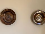 two metal bowls on the wall next to each other