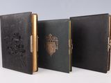 trois livres en cuir noir, avec des bordures dorées et une couronne sur la couverture