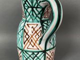 a green and white vase with a design on it
