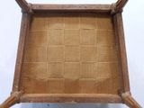a small wooden chair with a woven seat on it