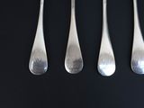 four silver spoons are lined up on a black surface