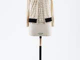 un pull blanc et une veste posés sur un présentoir pour mannequin