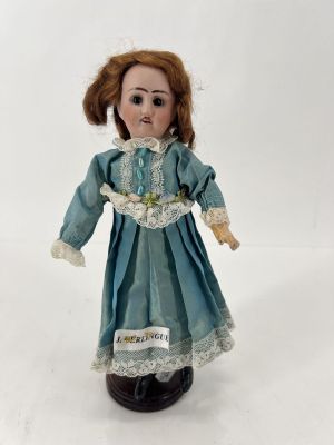 une poupée qui porte une robe bleue et un chapeau