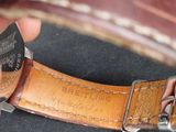 a person holding a watch with a leather band