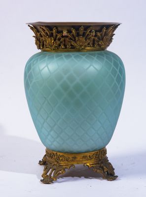 un vase bleu avec un socle doré sur fond blanc