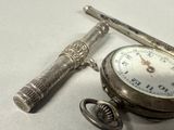 a pocket watch and a pen sitting on a table