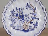 a blue and white plate with a bird and a tree on it