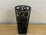 black and white shot glass on a wooden table with a white wall in the background