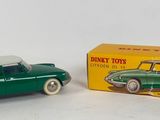 green toy car in front of a yellow box on a white surface