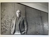 black and white photograph of a man in a suit standing in front of a wall