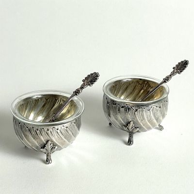 pair of silverplated bowls with spoons and spoons in them