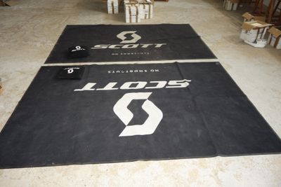 two black mats with white logos on them in a warehouse