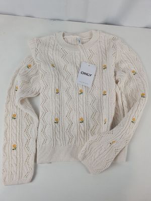 Le pull est blanc et comporte des boutons.