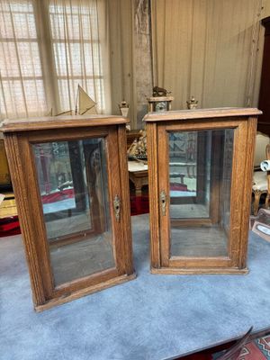deux armoires en bois avec des portes vitrées, posées sur une table