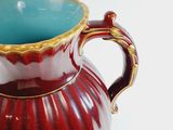 a red and gold vase with a blue inside of it