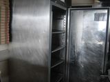 a large metal refrigerator in a room with a lot of shelves