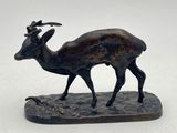 bronze statue of a goat on a rock with a white background