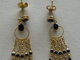 a pair of black and gold earrings on a white surface