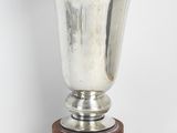 un vase en argent posé sur un socle en bois