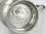 a silver cup sitting on a white surface with a hole in it